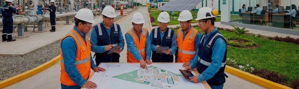 Jóvenes profesionales revisando planos en una planta de hidrocarburos.