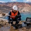 Técnico de campo con equipo de protección monitoreando una poza de agua en una operación minera